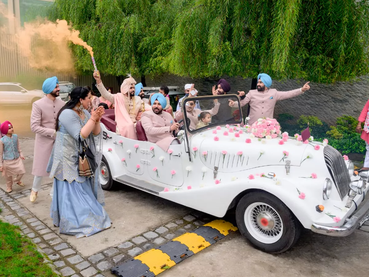 Bride Seating in White Antique Vintage Car decorated with White and Pink Roses